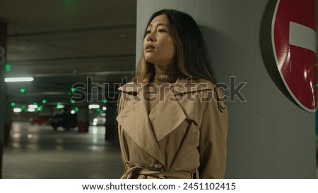 Frightened Asian ethnic chinese korean woman hiding from danger pursuit threat phobia in underground shelter night dark car parking scared fearful girl stand alone near stop driving traffic road sign