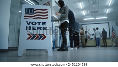 Vote here sign on the floor. Multi ethnic American citizens vote in booths in polling station office. National Election Day in United States. Political races of US presidential candidates. Civic duty.