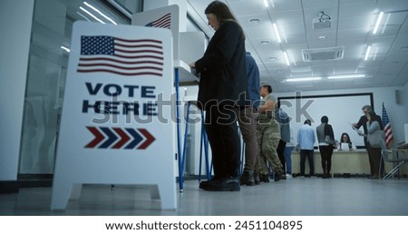Vote here sign on the floor. Multi ethnic American citizens vote in booths in polling station office. National Election Day in United States. Political races of US presidential candidates. Civic duty.