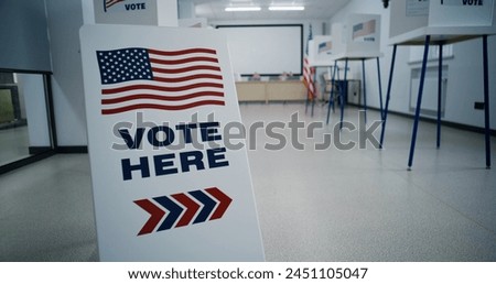Sign with American flag logo calling for voting. Voting booths in polling station office. Election Day in United States of America. Political races of US presidential candidates. Civic duty concept.