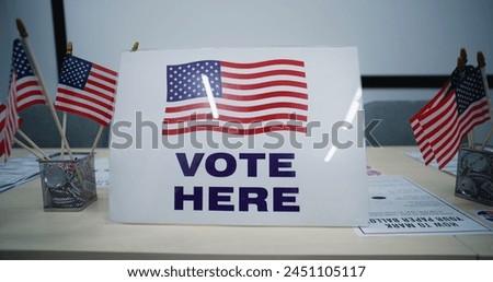 National Election Day in the United States of America. Sign with American flag logo standing on the table, calling for voting in polling station office. Political races of US presidential candidates.