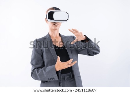 Business woman holding something while wearing VR goggle and standing at white background. Project manager with headset enter visual reality world program by using technology innovation. Contraption.