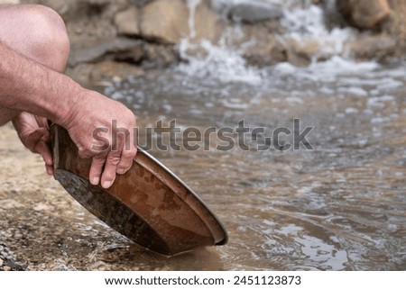 Searching for gold with an iron pan in a riverbed in Ballarat, Victoria, AustraliaGold panning Royalty-Free Stock Photo #2451123873