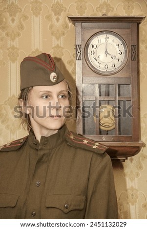 A woman in a military uniform against the background of old paper wallpaper and a clock with a pendulum. Vintage styling.