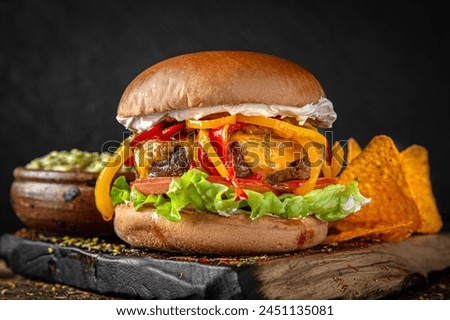 Gourmet Burger with beef patty, grilled vegetables, cheese and sauce. Juicy delicious hamburger on darkmood picture for restaurant decoration, poster. 