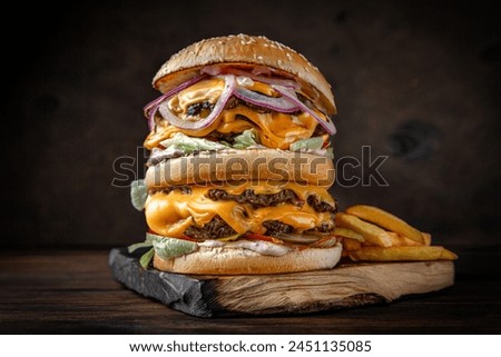 Double superburger with beef patties, cheese, vegetables, gravy and iceberg lettuce. Juicy delicious hamburger on darkmood picture for restaurant decoration, poster. 