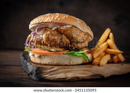 Burger with kebab meat, cheese, vegetables, sauce and iceberg lettuce. Juicy delicious hamburger on darkmood picture for restaurant decoration, poster. 