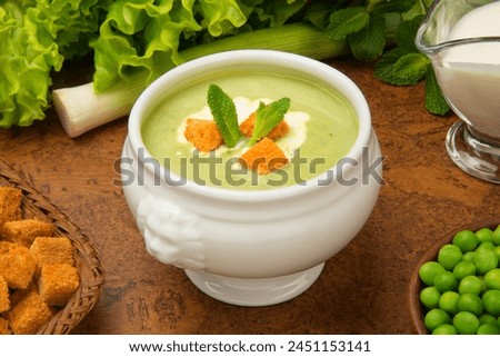 French pea soup "Saint Germain" in a white tureen with ingredients on a brown table. Royalty-Free Stock Photo #2451153141