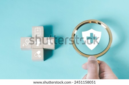 Health insurance and medical welfare concept, Hand holding a magnifying glass plus and medical icons on a wooden block Health and access to health care, good health and lifestyle