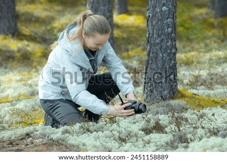 A woman takes a picture of forest nature with a camera