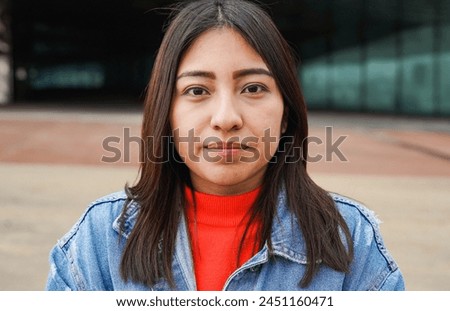 Portrait of native american woman looking on camera with city in background - Indigenous girl outdoor
