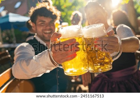 Two people in traditional tracht clinking beer mugs and smiling at sunny day at oktoberfest or beer garden in germany Royalty-Free Stock Photo #2451167513