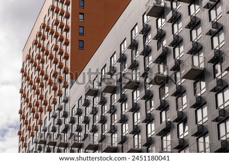 Residential complex in Moscow. New buildings in Moscow, high-rise bright creative house and against the sky. There are many apartments with Windows. Royalty-Free Stock Photo #2451180041