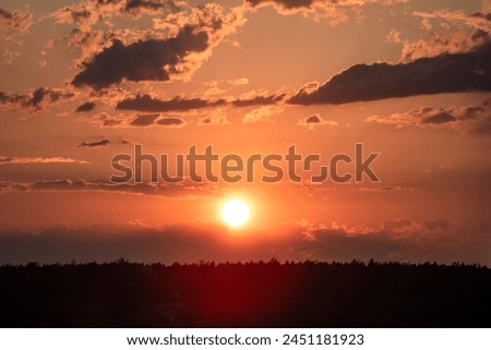 Concept for desktop background, natural texture, nature. The sun sets over the forest over the horizon against the backdrop of the summer evening sky. Kyiv, Ukraine, Europe.