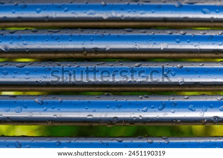 Close-up of metal bars of bench covered with water drops at City of Wallisellen on a sunny spring day. Photo taken April 18th, 2024, Wallisellen, Canton Zürich, Switzerland.