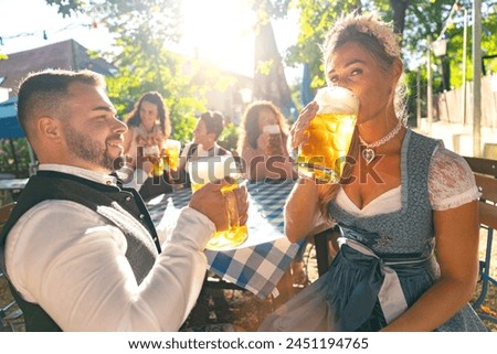 Young people in Tracht, Dirndl and Lederhosen having fun in Beer garden in Bavaria, Germany Royalty-Free Stock Photo #2451194765
