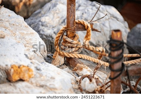 Rope tied to a wooden post on the beach. Detail with anchor and rope