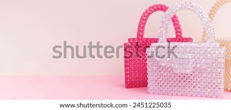 Banner with handcraft bags made from beads in front of beige and pink background.