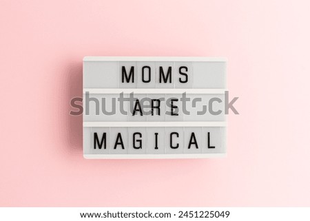 Moms are magical. White lightbox with letters on a pink background. 