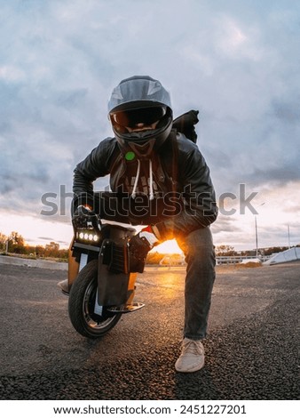 rider in a helmet with sunglasses rides on an electric mono wheel. Royalty-Free Stock Photo #2451227201