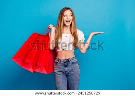 Portrait of lovely young girl arm hold empty space ad wear top isolated on blue color background