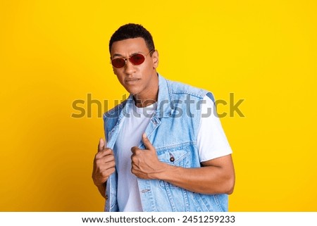 Photo of cool handsome guy stylish haircut dressed jeans waistcoat in glasses holding jacket isolated on vibrant yellow color background