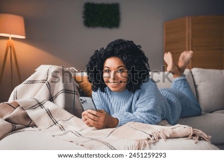 Full size photo of pretty young woman lying couch hold smart phone wear sweater modern interior apartment indoors
