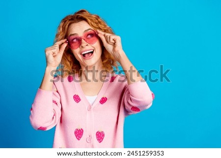 Photo of attractive young woman touch sunglass have fun look empty space dressed stylish pink clothes isolated on blue color background