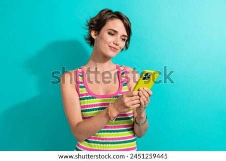 Photo of gorgeous positive lady use smart phone typing blog post texting isolated on teal color background