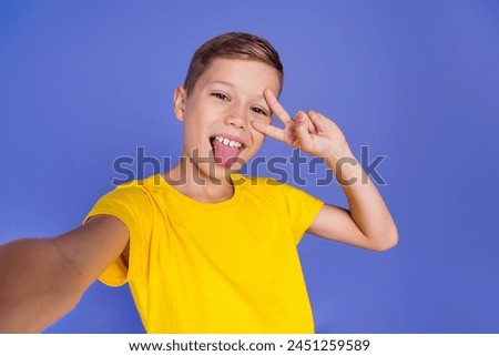 Photo of cheerful positive funny child boy wear stylish yellow clothes have fun live stream isolated on purple color background