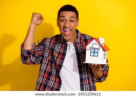 Photo of overjoyed man dressed plaid shirt raising fist scream yeah win new house in lottery isolated on vibrant yellow color background
