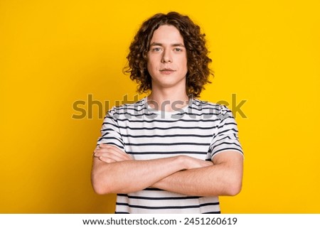 Photo of nice young man crossed arms wear striped t-shirt isolated on yellow color background