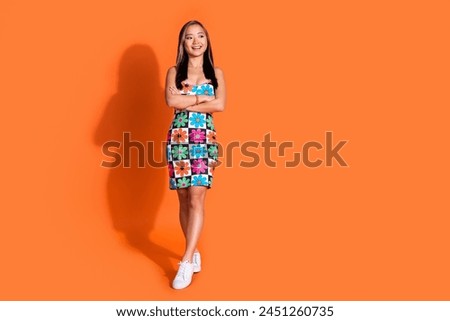 Full length photo of nice pleasant woman dressed flower print clothes look empty space arms folded isolated on orange color background