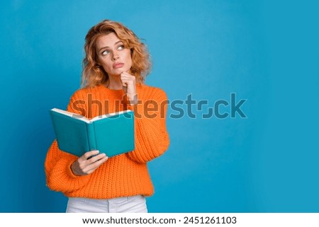 Photo of minded sad upset woman wear stylish orange clothes hold book look empty space isolated on blue color background