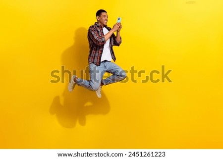 Full size photo of nice man dressed plaid shirt jeans trousers flying make photo on smartphone isolated on vivid yellow color background