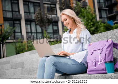 Side profile photo of young blond wavy hair cheerful woman sitting stairs outdoors near university campus typing email for lecturer