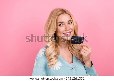 Portrait of cute person with curly hair wear blue cardigan hold credit card look at promo empty space isolated on pink color background