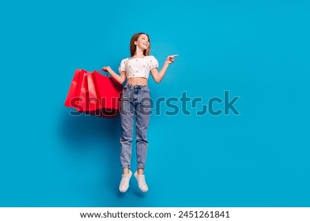 Full size photo of nice young girl jump point finger empty space wear top isolated on blue color background