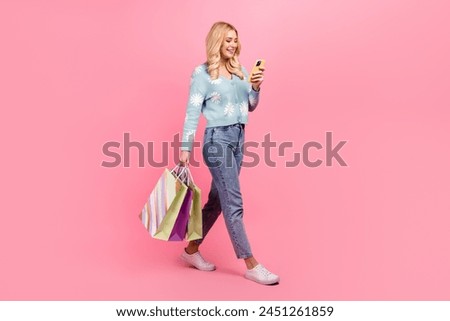 Full size photo of lovely young woman hold shopping bags device walk dressed stylish flower print garment isolated on pink color background