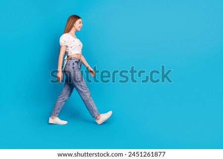 Full size profile photo of nice young girl look walk empty space wear top isolated on blue color background