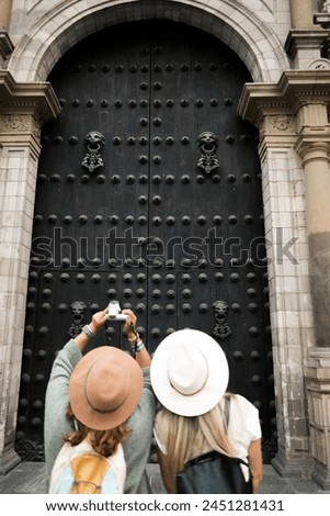 A tourist takes a photograph in front of the door of the cathedral of Lima, Peru.