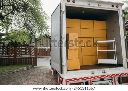 House relocation, Open car trunk with moving cardboard boxes outdoors. White delivery van for logistic transport service. Busy moving day. Moving Day Concept. Royalty-Free Stock Photo #2451311567