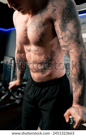 close-up in the gym of the torso of a young handsome guy with tattoos of the abs and pectoral muscles Royalty-Free Stock Photo #2451323663