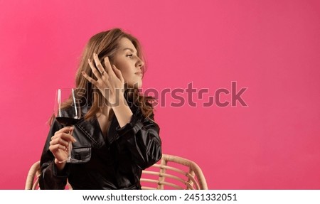 beautiful woman holding glass with red wine isolated on pink background.blonde girl in leather dress with bouquet of tulips.large banner free space for text.