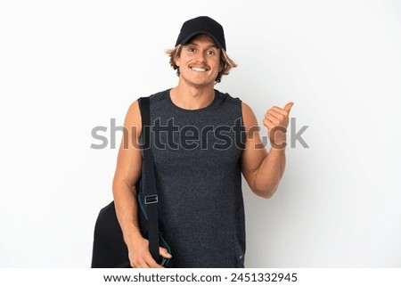 Young sport man with sport bag isolated on white background pointing to the side to present a product