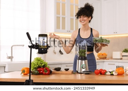 Smiling food blogger explaining something while recording video in kitchen Royalty-Free Stock Photo #2451333949