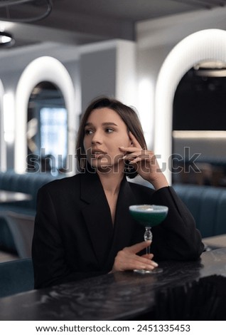 beautiful woman in restaurant drinking cocktail at bar countertop or eating sweet desert,hot napoleon.girl in night dress with glass of wine in hand.restaurant business advertising photography