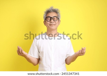 Chinese Vegetarian Festival. Senior man wearing white clothing with gesture of standing meditation isolated on yellow background. Nine emperor god, J festival.