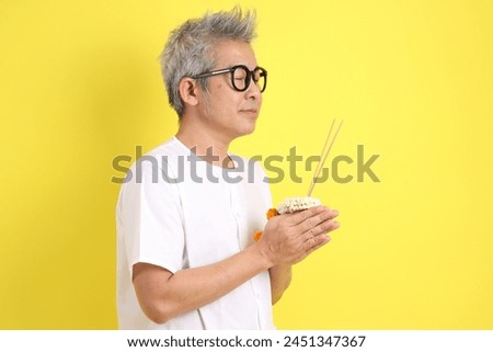 Chinese Vegetarian Festival. Senior man wearing white clothing with gesture of hand holding thai flower garland and  incense sticks isolated on yellow background. Nine emperor god, J festival.