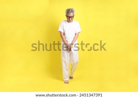 Chinese Vegetarian Festival. Senior man dress in white color with gesture of Walking meditation  isolated on yellow background. Nine emperor god, J festival.